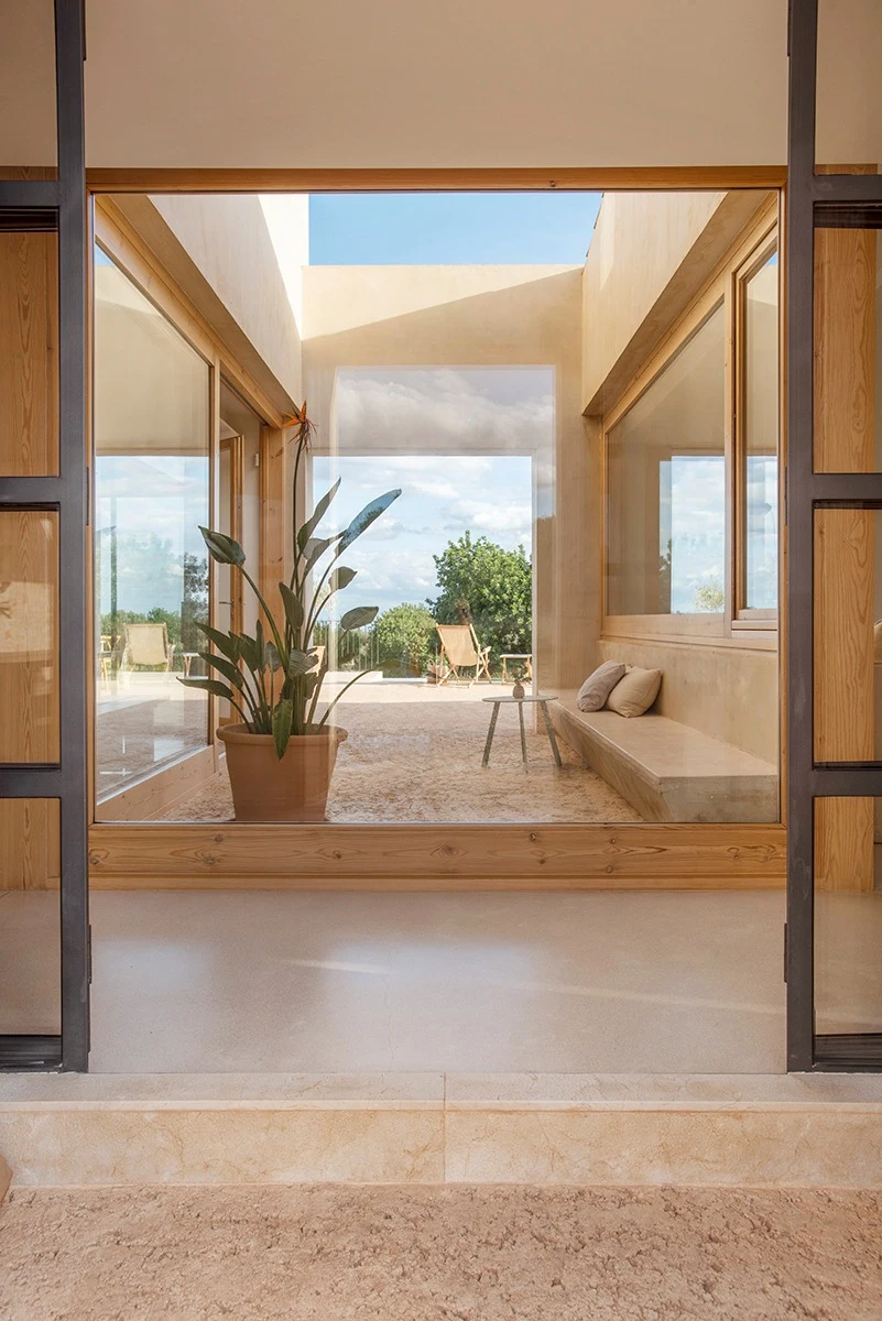 Casa LLT: pati de tons càlids emmarcat per les fusteries de fusta