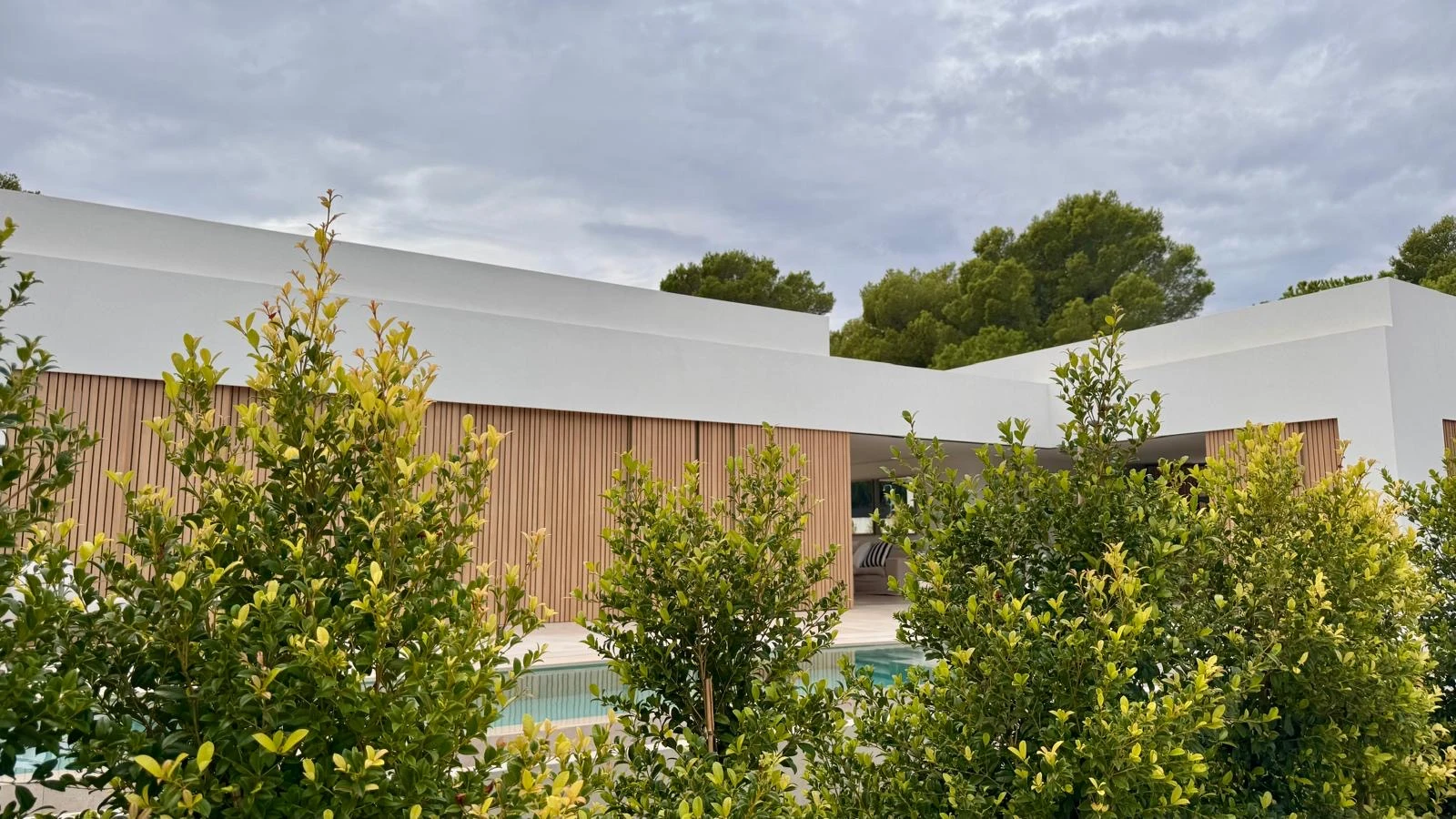 Son Serra: Façanes blanques i tancaments de fusta entre la vegetació del jardí